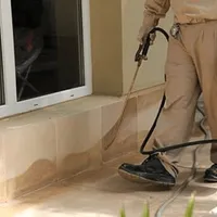 General pest control technician spraying exterior perimeter around a home in Mobile, AL