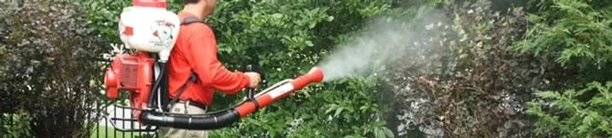 Mosquito control technician fogging shrubs and landscaping for mosquito treatment in Mobile, AL