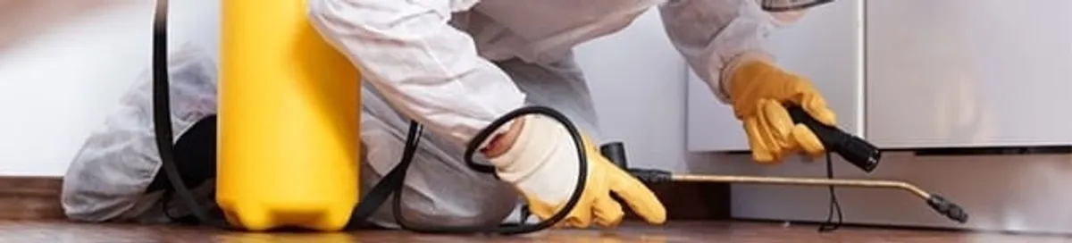Roach exterminator treating cracks and crevices along kitchen baseboards in Mobile, AL